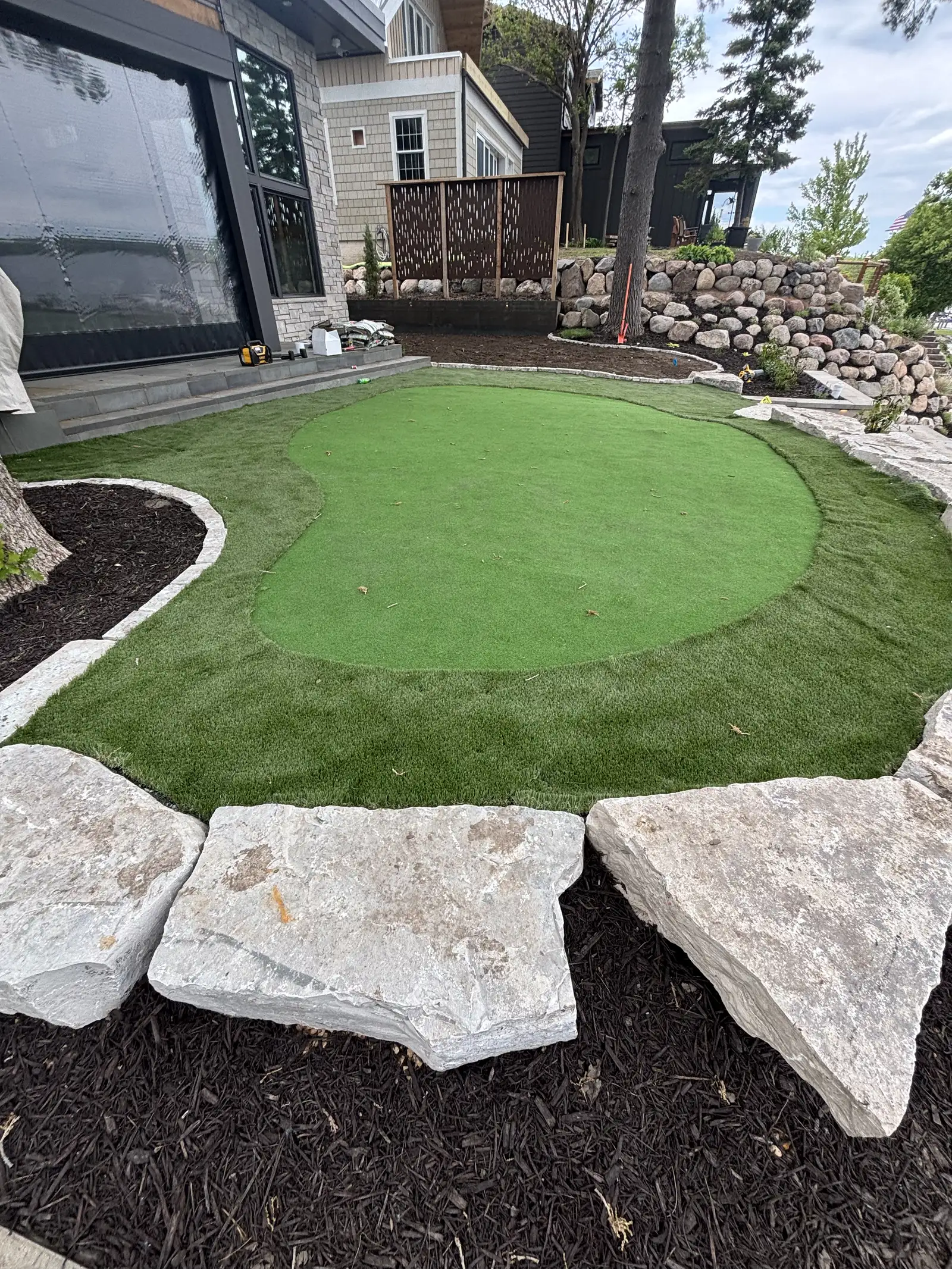 Custom artificial turf putting green with natural boulder edging in Excelsior, MN