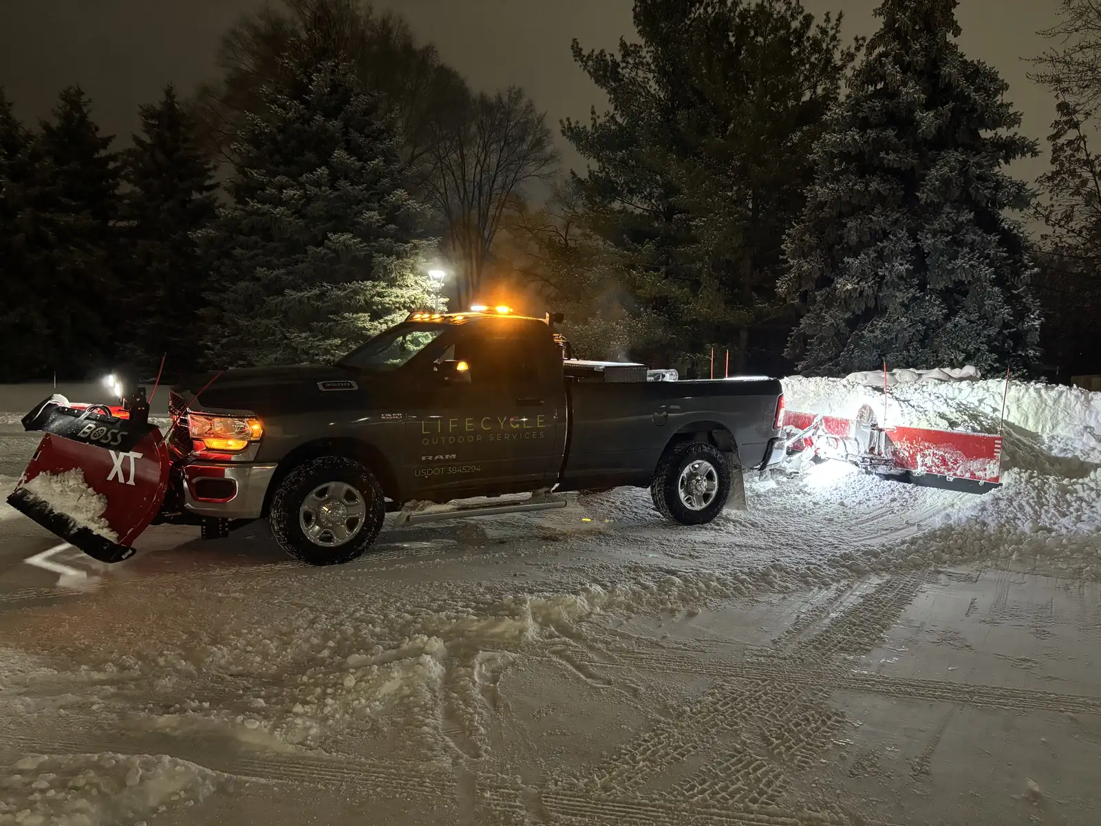 Lifecycle Outdoor Services plow truck actively plowing during a Minnesota snowstorm at night