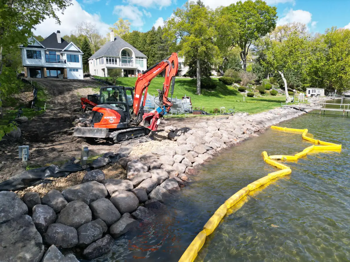 Excavator placing rip rap boulders for Lake Minnetonka shoreline stabilization in Orono, MN