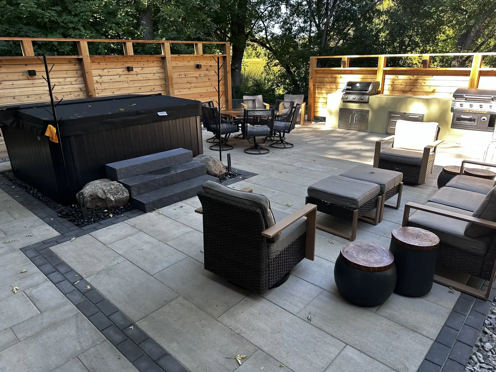 Completed paver patio with outdoor furniture, hot tub, and cedar privacy screening in Waconia, MN